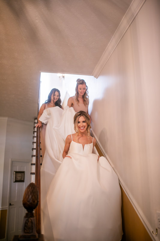 bridesmaids helping bride walking down farmhouse stairs