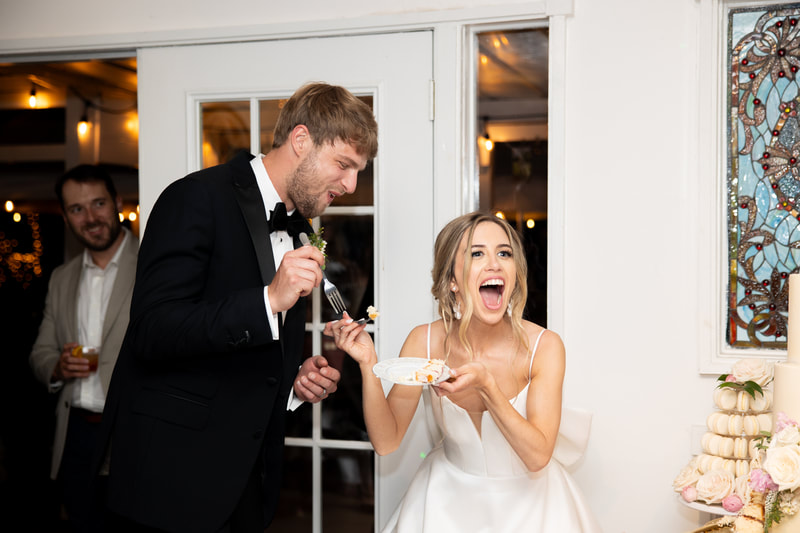 bride reacting to groom eating wedding cake at farmhouse reception