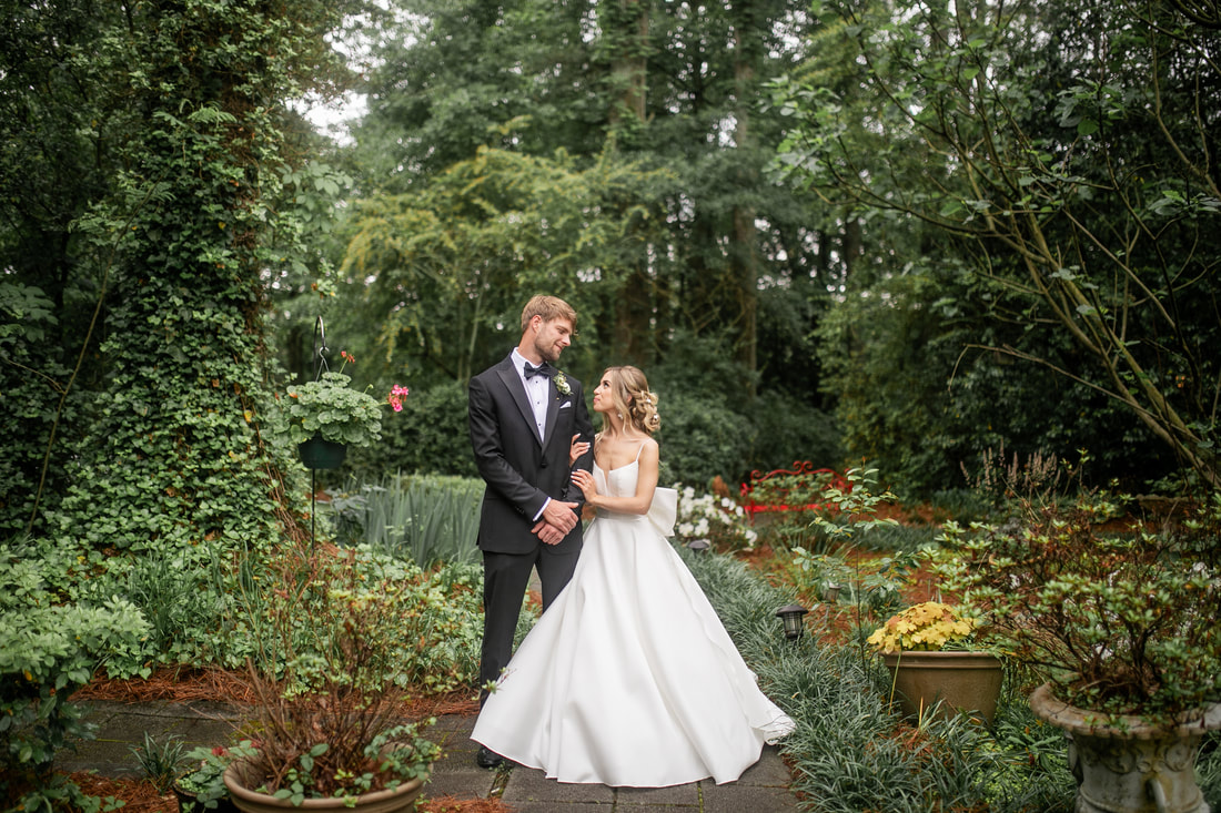 bride and groom posing along lush garden path