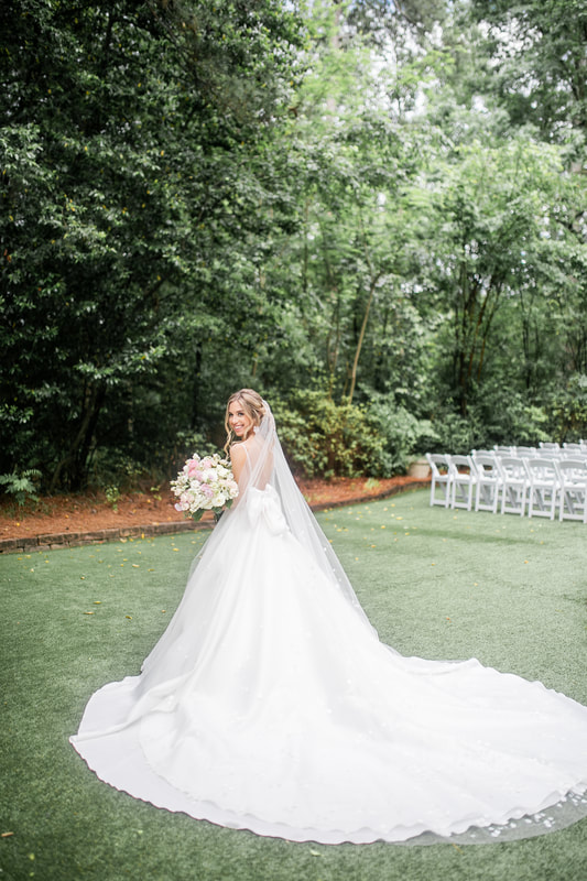 bride with large train standing in garden ceremony space