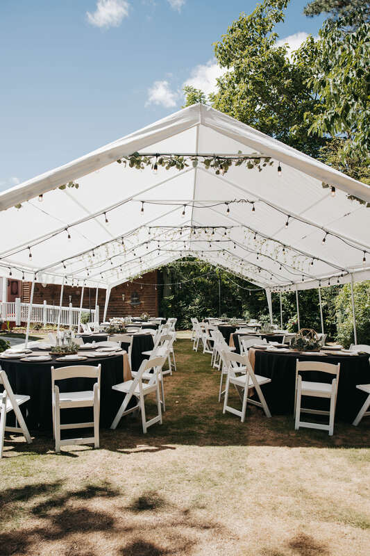 Tented summer wedding reception tables with black table cloths and champagne decor