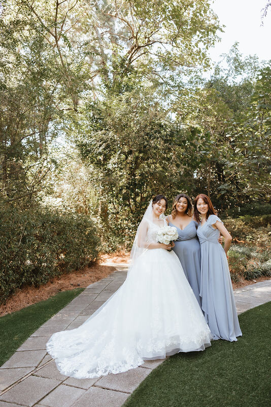 bride and bridesmaids in light blue dresses standing in garden venue