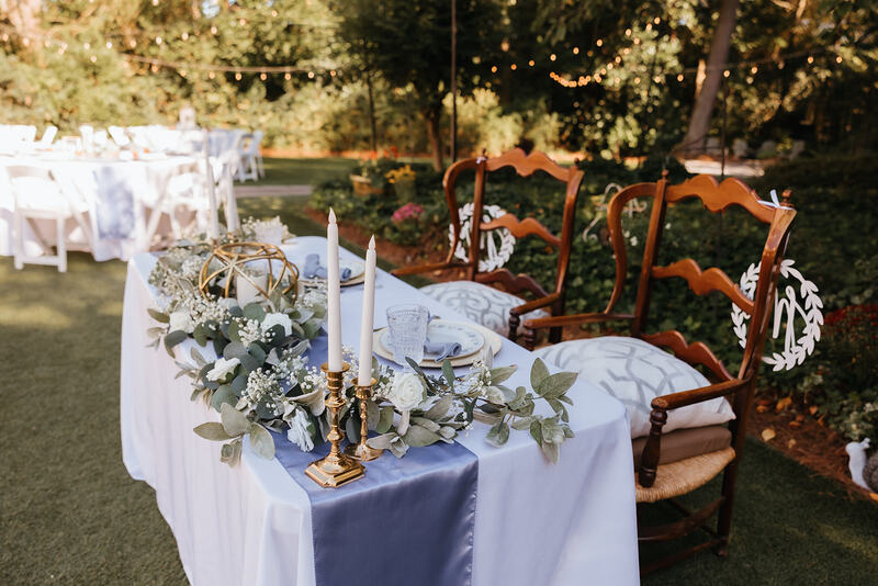 sweet heart table decorated with greenery, white flowers, and candles