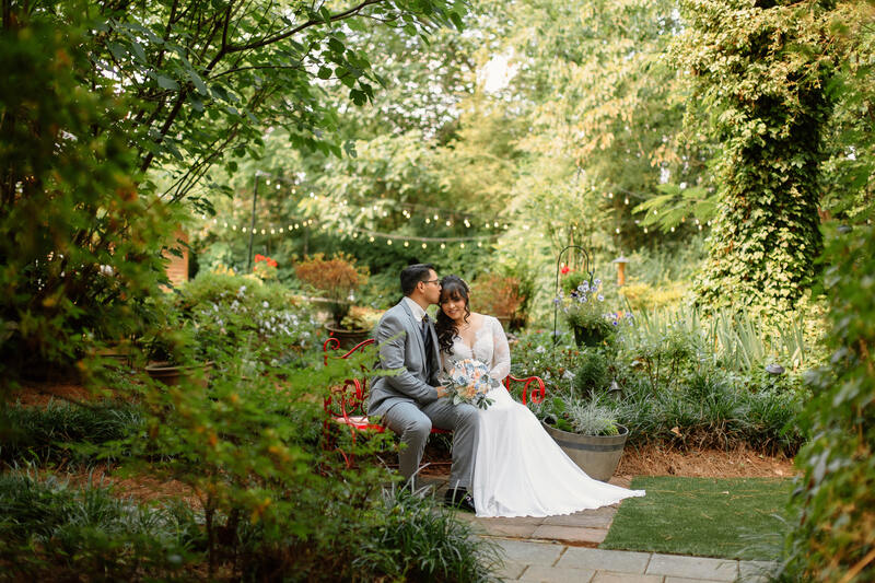 newlyweds sitting on red bench in garden