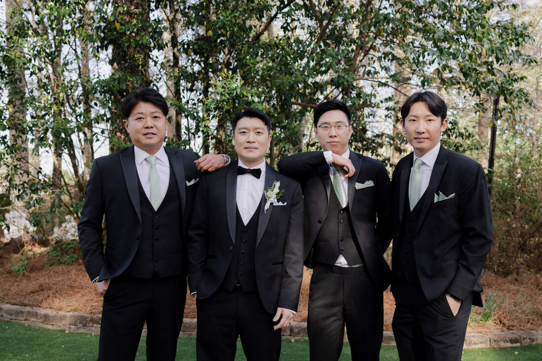 groom and groomsmen in black suits with sage green ties
