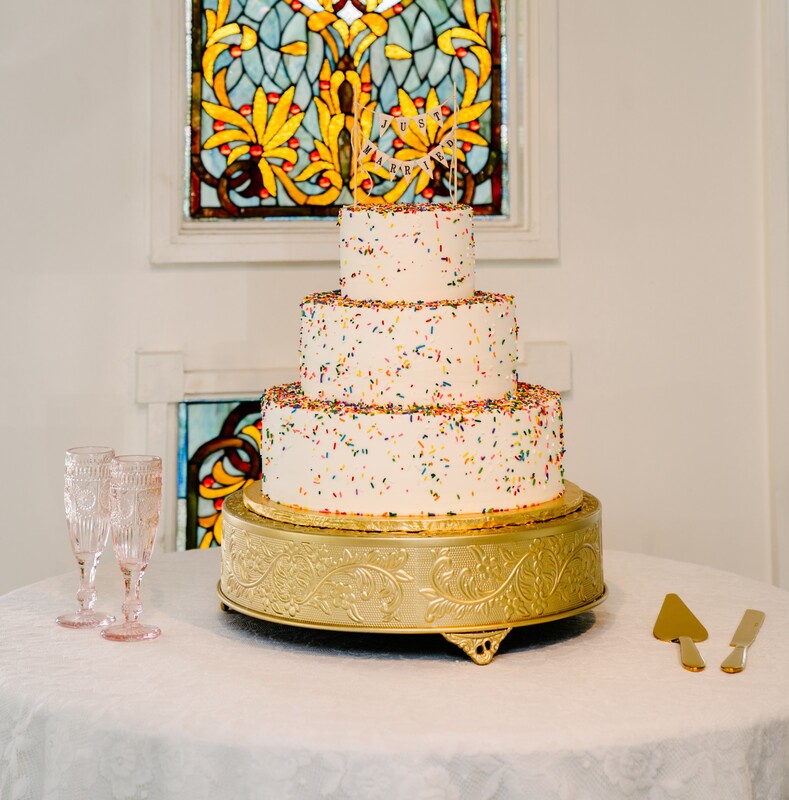 Fun confetti wedding cake with gold stand & pink champagne flutes
