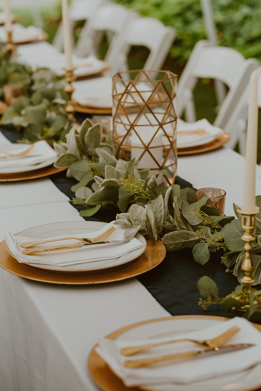 rectangle table with gold place settings, navy linens, and greenery