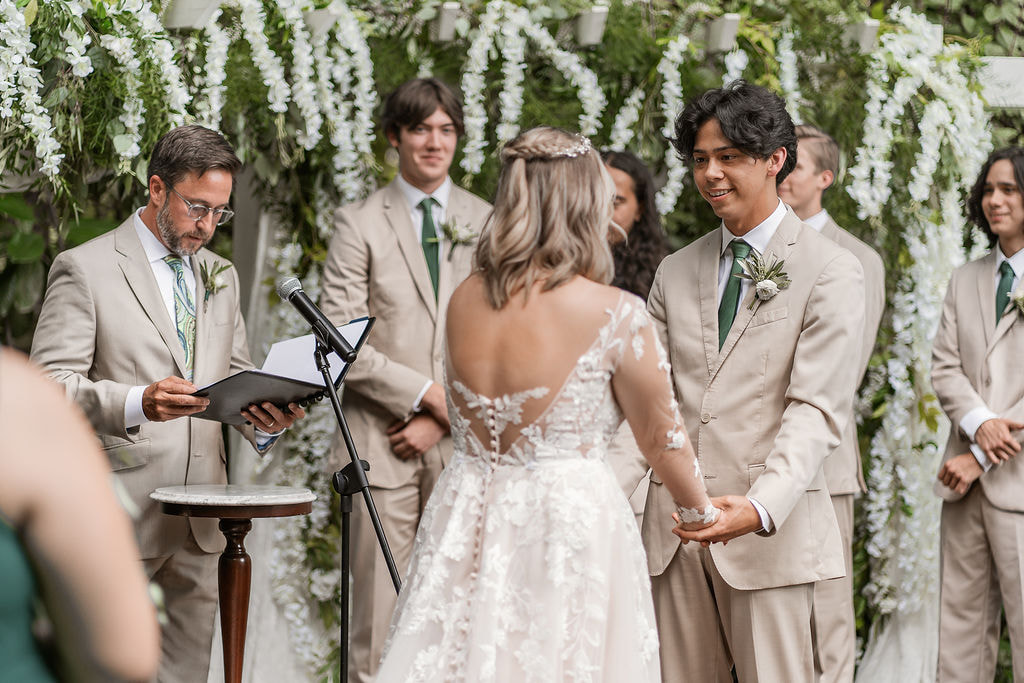 garden wedding ceremony with greenery and wisteria covered altar