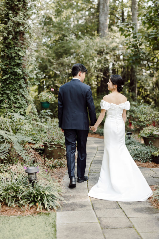 korean bride and groom walking through garden path