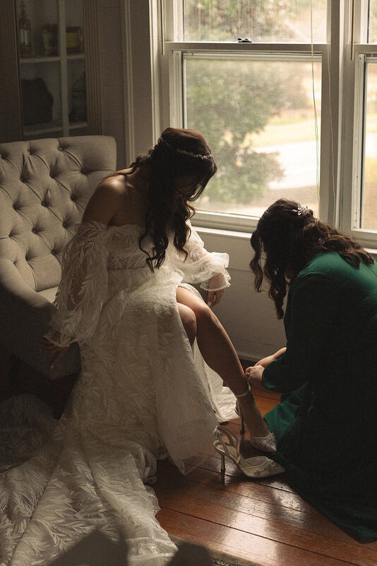 bridesmaid putting bride's shoes on
