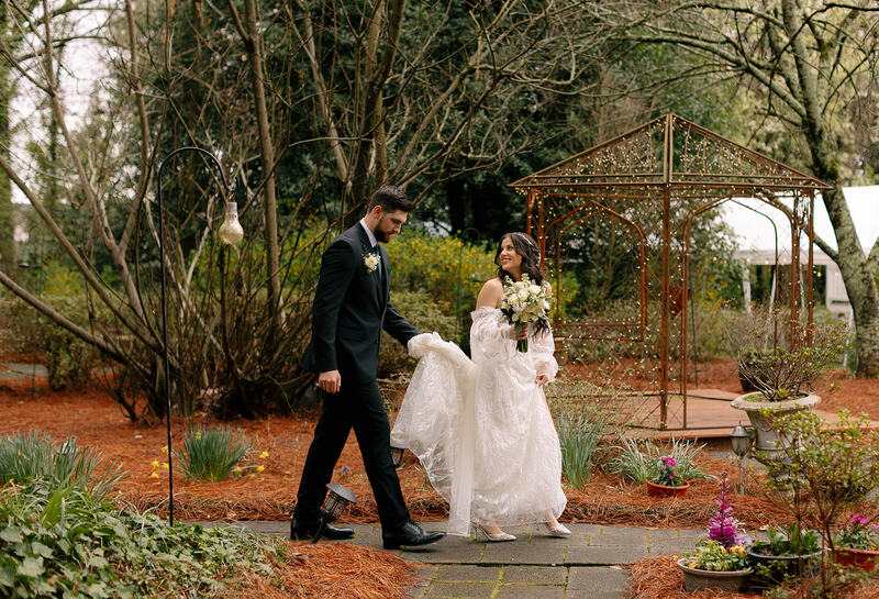 bride and groom walking through garden path