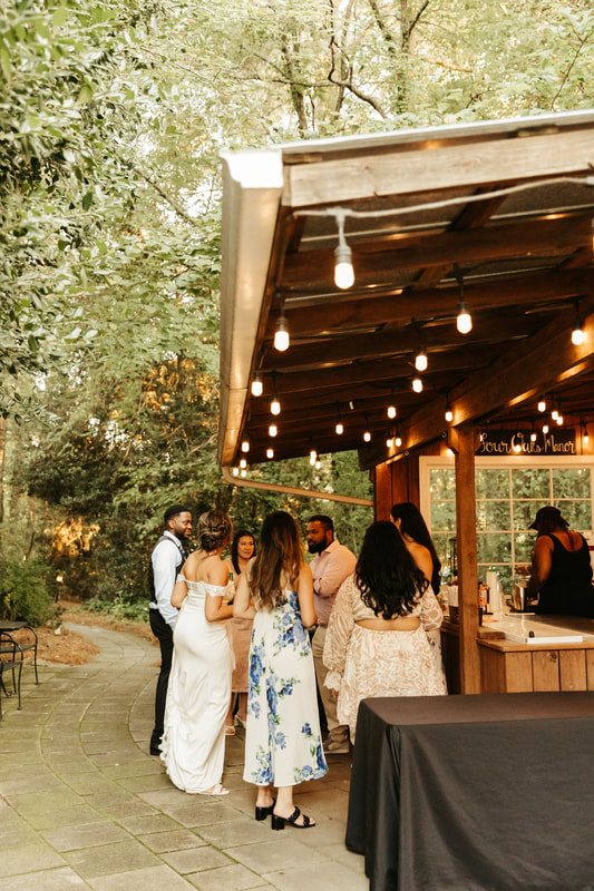 bride and groom with guests at rustic garden bar
