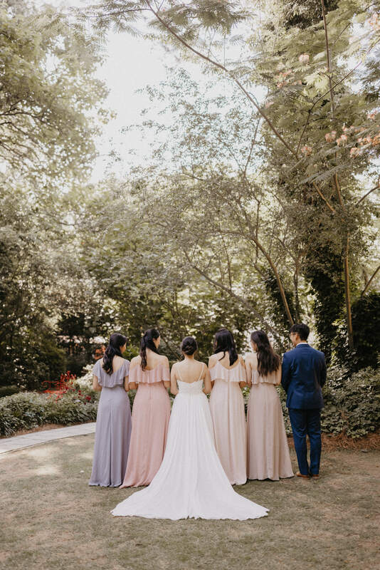 blush and blue bridal party posing with bride in garden