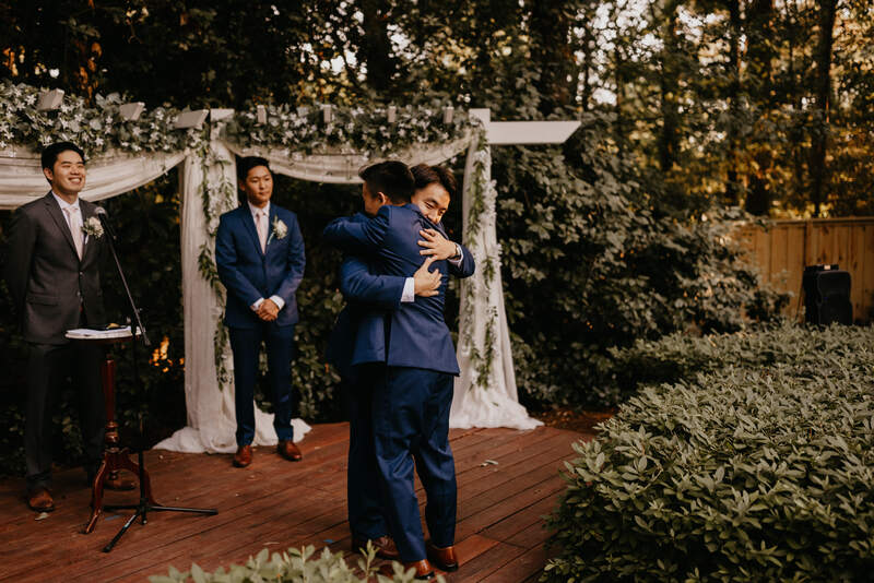 groom and groomsman hug at outdoor altar