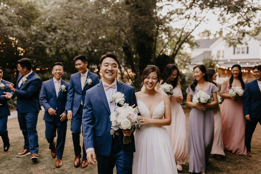 bride and groom walking with navy and blush wedding party