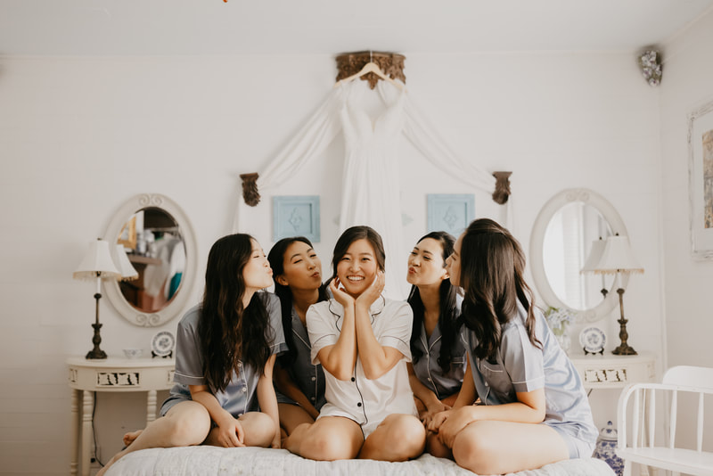 bride and bridesmaids posing on farmhouse bed