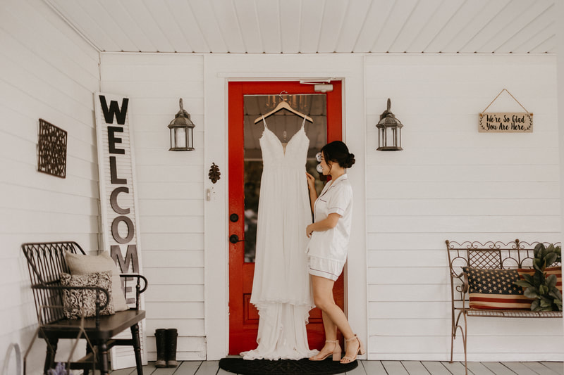 bride with wedding dress hanging on farmhouse red door