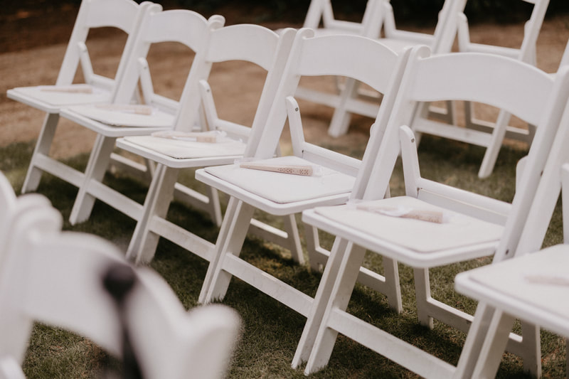 white wedding chairs with fans on them