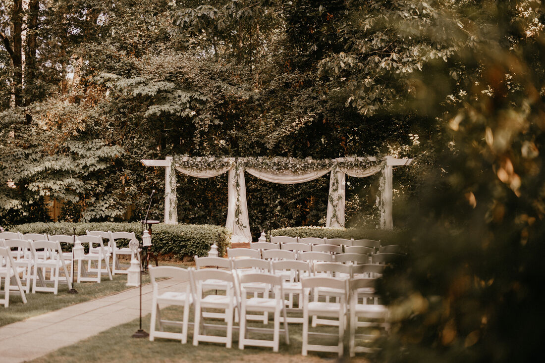 garden ceremony with drapes and greenery decorating the arbor