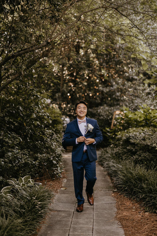 groom in navy suit with blush bow tie