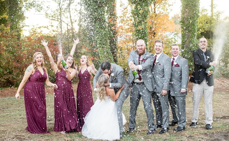 Picture of Samantha and Simon celebrating their marriage with champagne and bridal party.