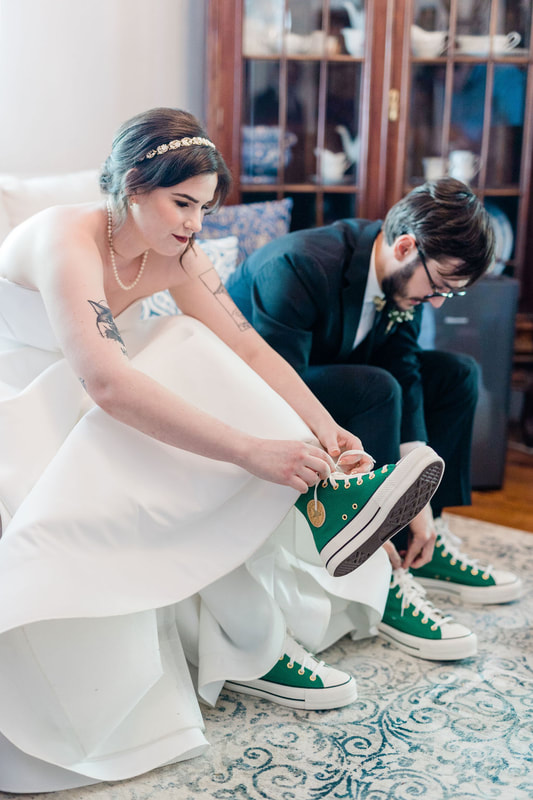 bride and groom putting on matching green converse