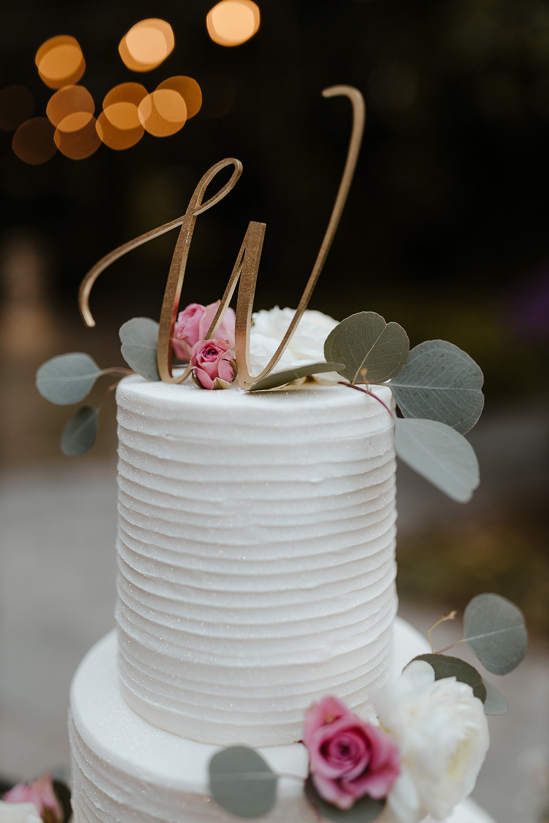 top-tier of white wedding cake with gold W cake topper