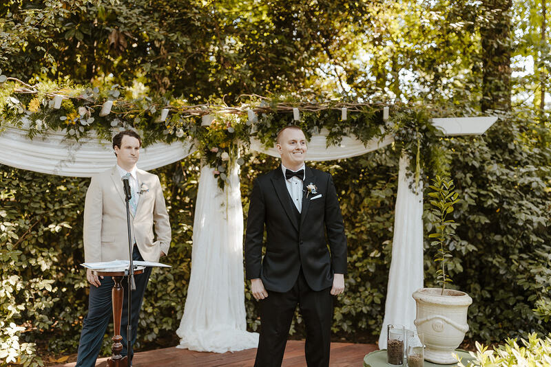 groom at outdoor altar covered with greenery