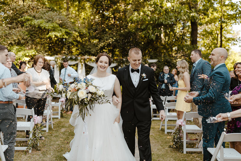 bride and groom walk down aisle as guests toss biodegradable potpourri