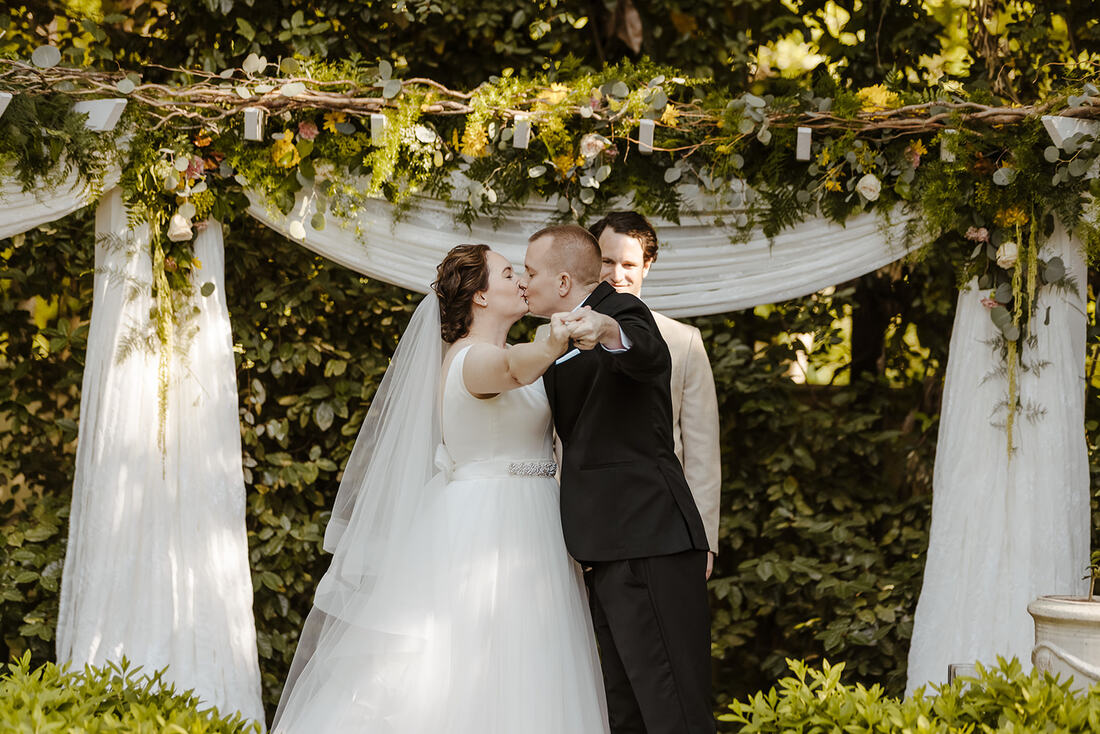 bride and groom kiss at garden altar