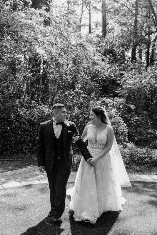 black and white photo of bride walking with and holding groom's arm