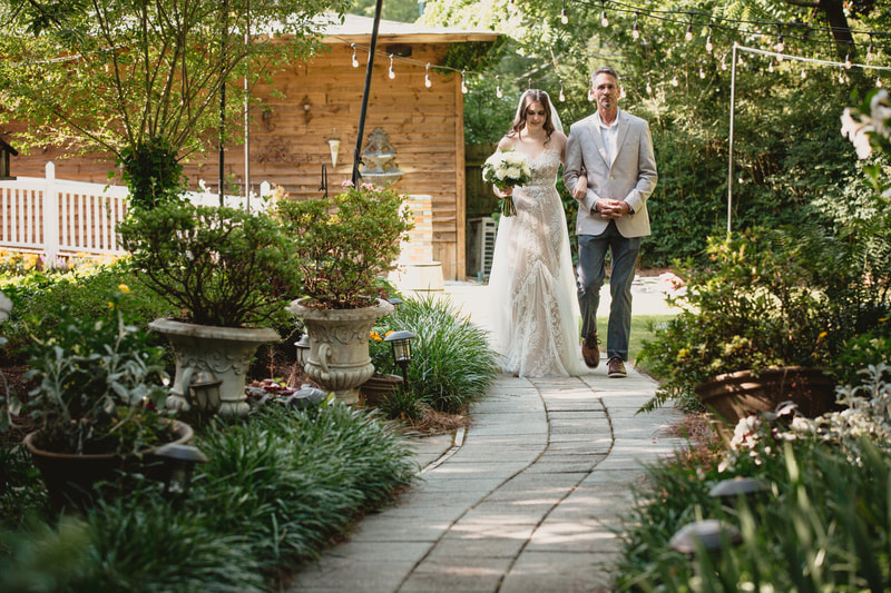 father walking bride down garden path during outdoor processional