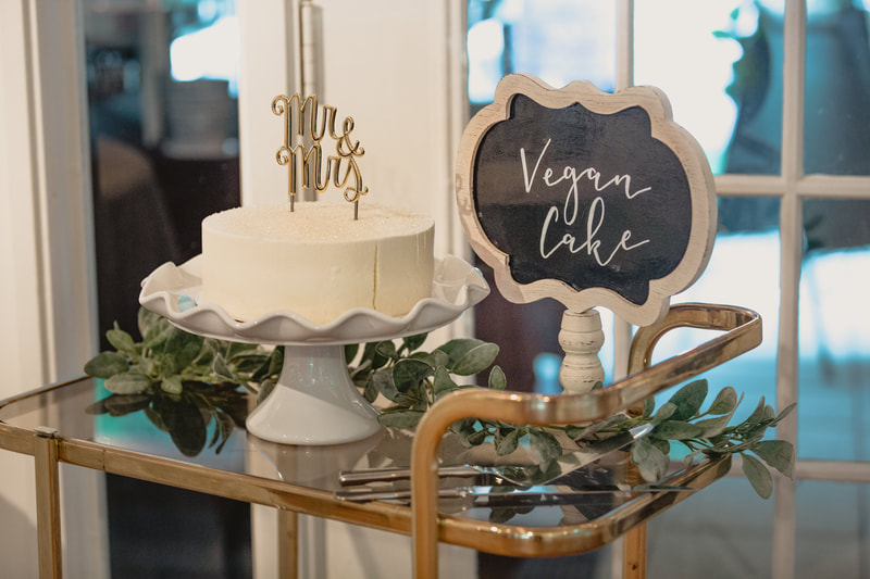 vegan cake on gold bar cart with cake topper and chalkboard sign