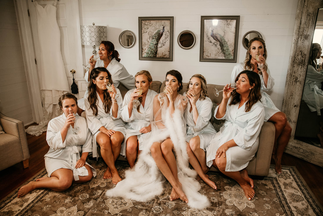 bride and bridesmaids sitting on sofa sipping champagne