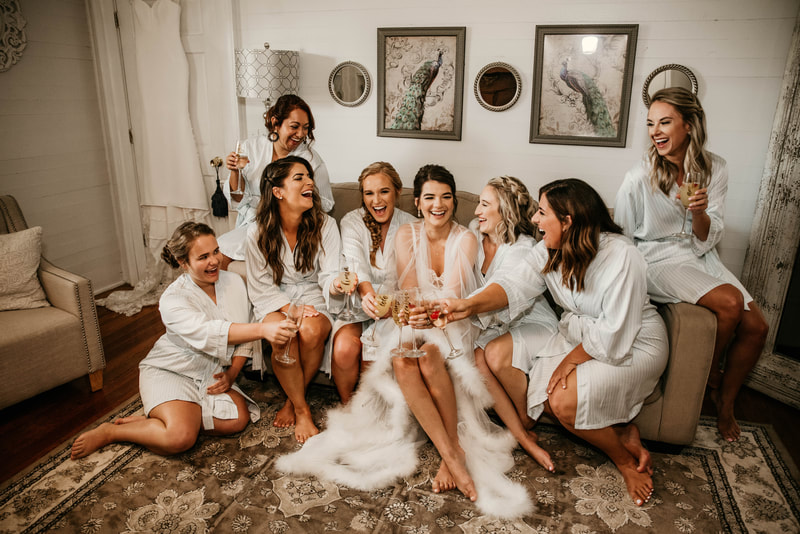 bride and bridal party in robes and holding champagne while getting ready