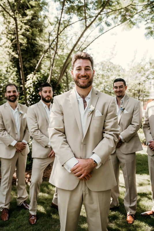groom in tan suit standing with groomsmen in matching suits