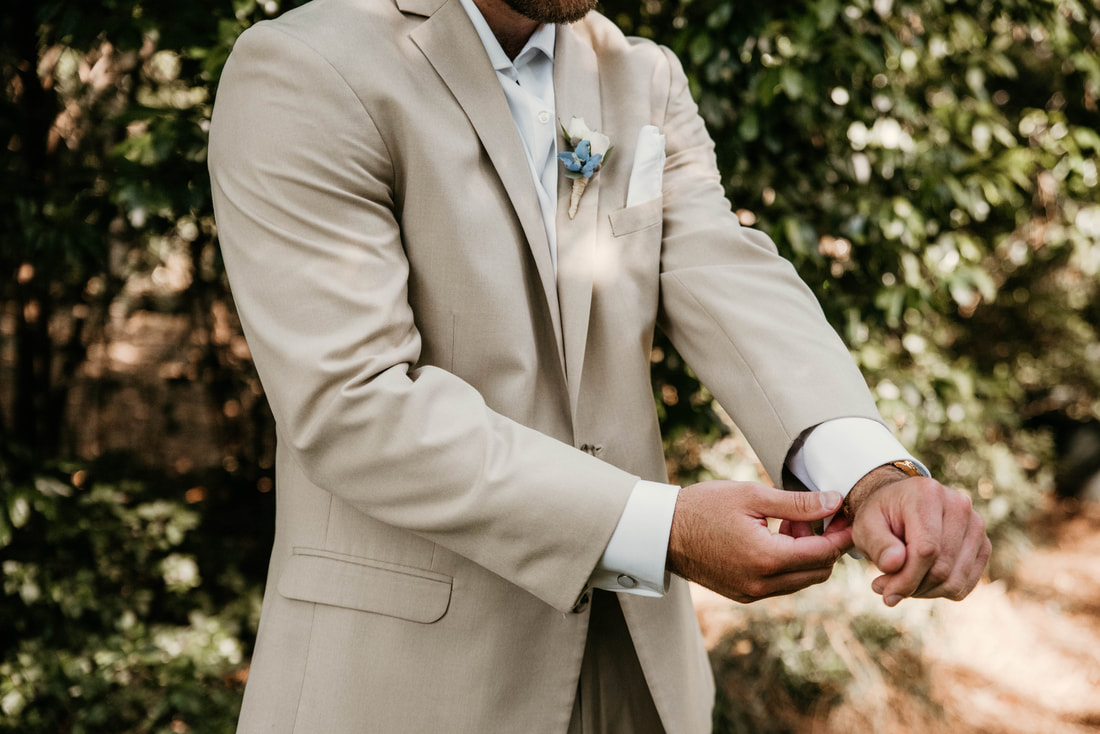 groom in tan suit fixing cuff