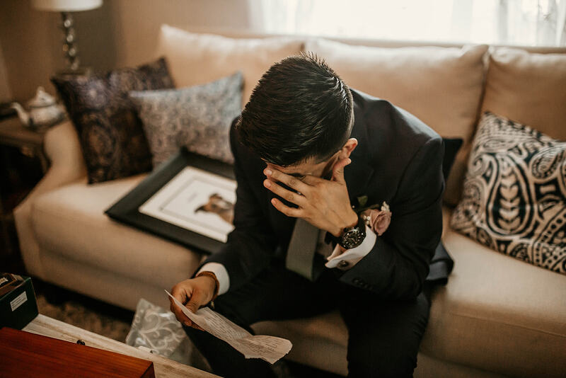 groom wiping away tears as he reads note from bride