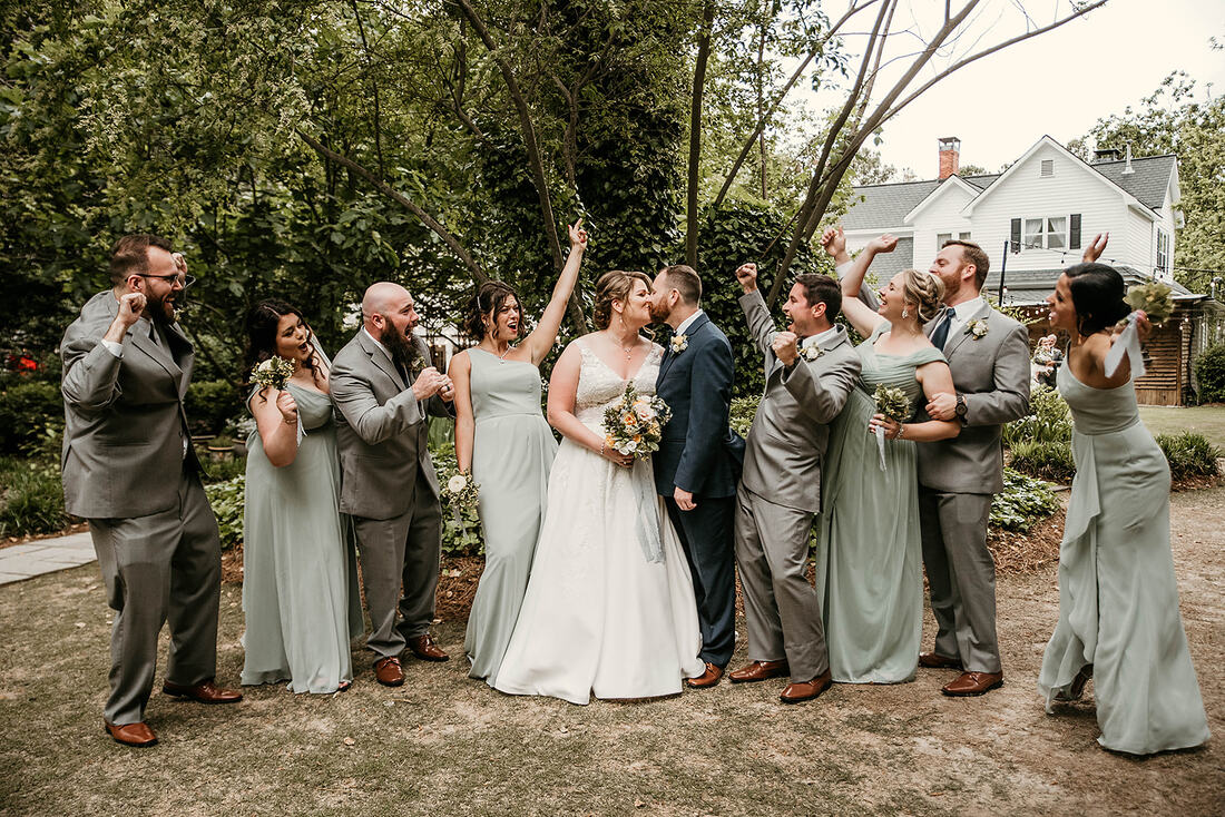 bride and groom kissing as wedding party cheers