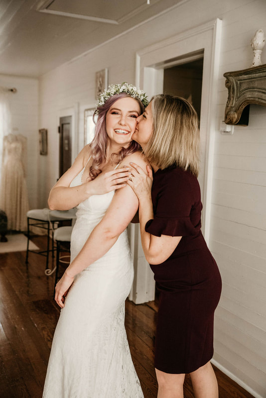 
mother of the bride kisses daughters cheek while getting ready