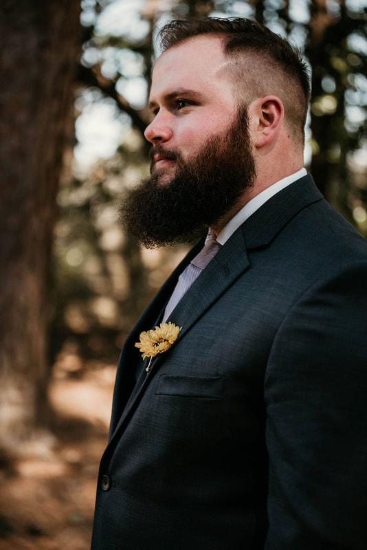 groom with yellow flower boutonniere posing outside