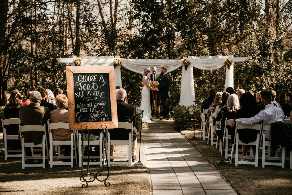spring wedding ceremony with sunflowers and chalkboard choose a seat sign