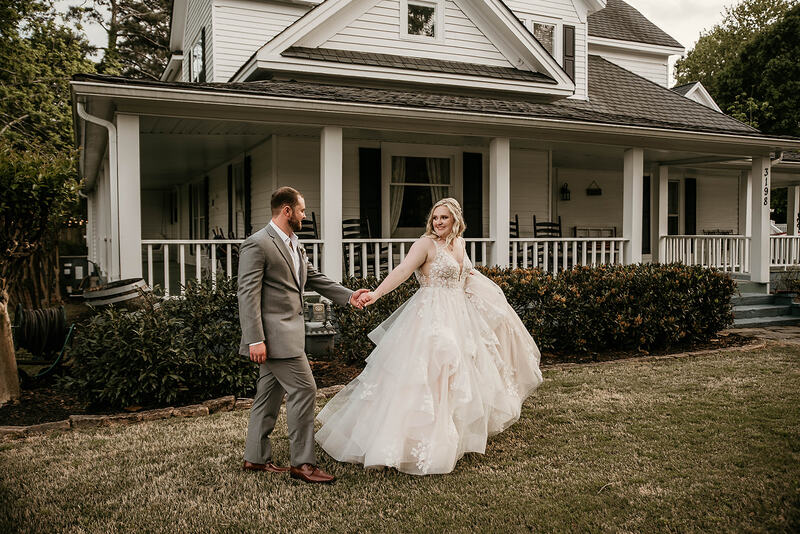 bride and groom walking in front of farmhouse