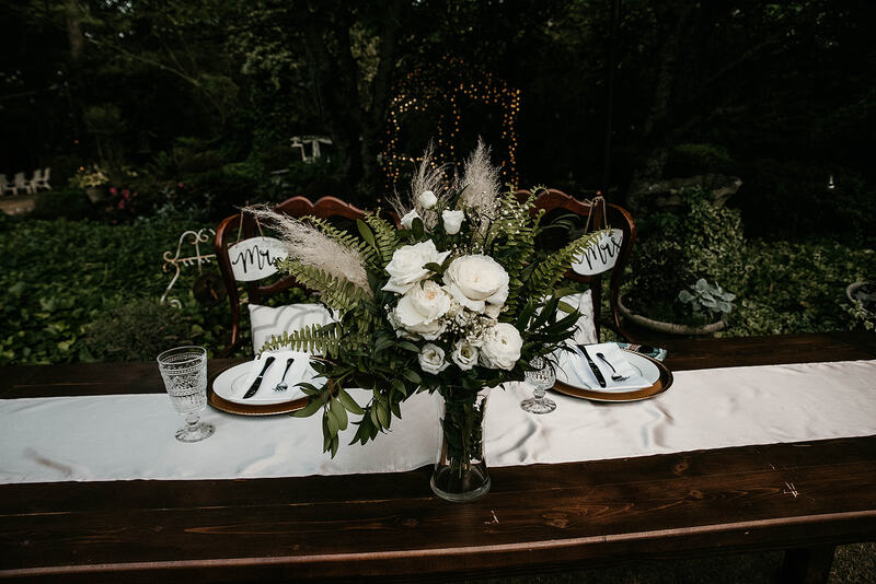 head table at outdoor garden reception with bride's bouquet as centerpiece