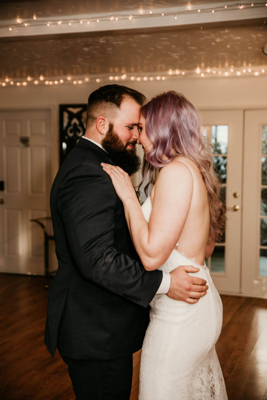 newlyweds dance in carriage house under string lights