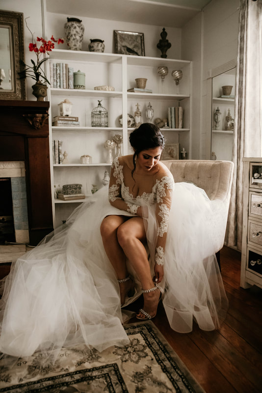 bride in ballgown dress fixing heels in bridal suite