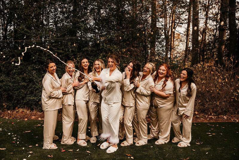 bride and bridesmaids in satin robes popping champagne
