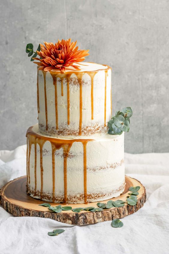 vegan vanilla wedding cake with eucalyptus leaves and an orange flower