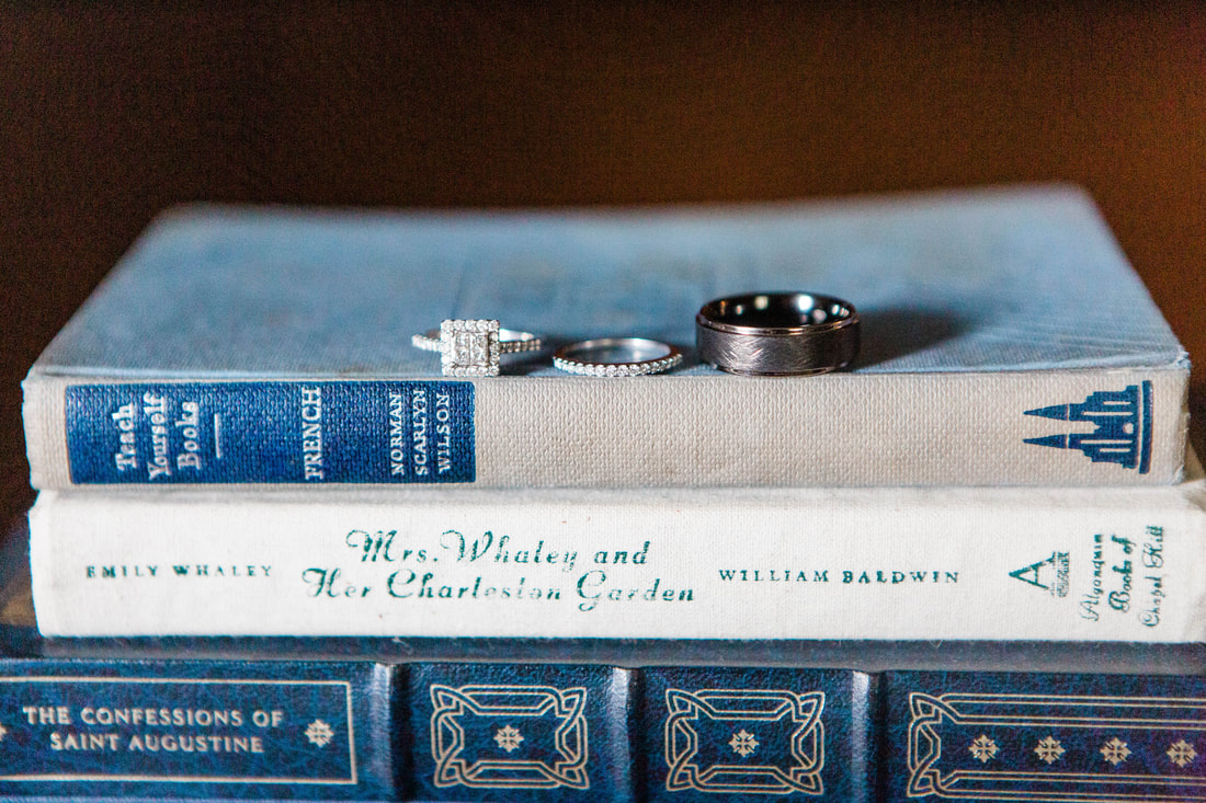 couple's rings sitting on stack of vintage blue books