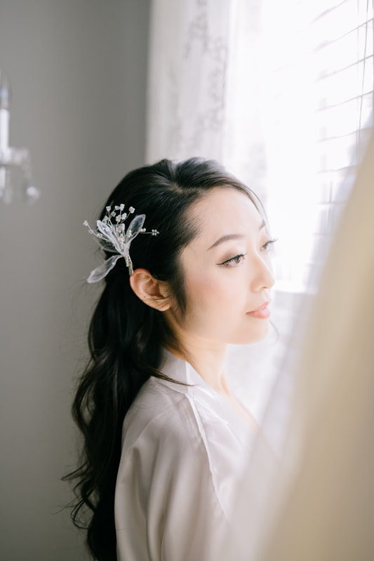 bride with floral hair piece looking out window